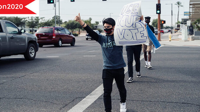 A Young Boy Holding Banner Of Use Your Vote